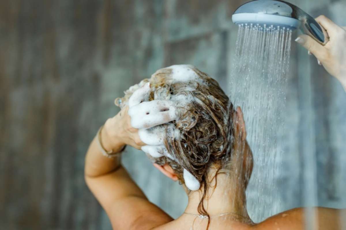 Donna si sta lavando i capelli sotto la doccia